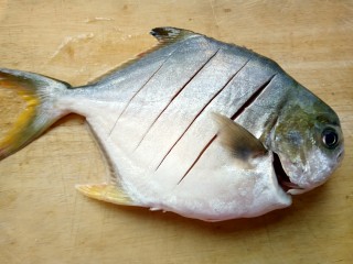秘制红烧鲳鱼,鱼放在菜板上斜切几刀