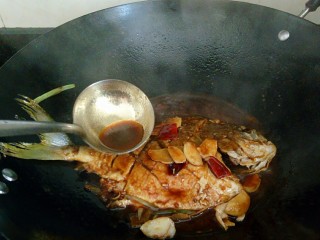秘制红烧鲳鱼,用勺子舀起汤汁不断浇到鱼身上，让鱼更入味