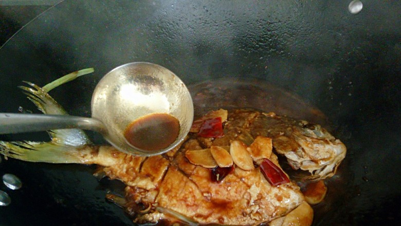 秘制红烧鲳鱼,用勺子舀起汤汁不断浇到鱼身上，让鱼更入味