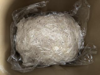 五谷桂圆软欧,混合好的面团铺平在面包机中，盖上保鲜膜静置5分钟，再打开发酵功能，发酵60分钟