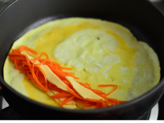 胡萝卜芝士蛋卷,待蛋液慢慢凝固，摆上胡萝卜丝和芝士片