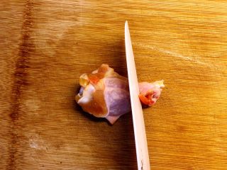 香烤鸡翅根,用刀在鸡翅根的底部切一圈，切断皮肉和筋膜。