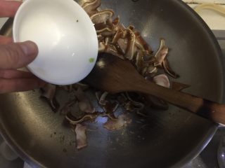 蒜苗木耳炒猪耳,加入少许清水翻炒，因为卤好的猪耳胶质很多很容易粘锅