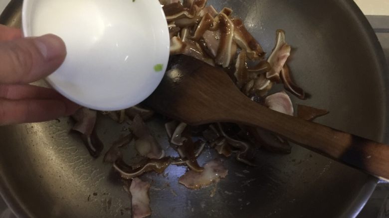 蒜苗木耳炒猪耳,加入少许清水翻炒，因为卤好的猪耳胶质很多很容易粘锅