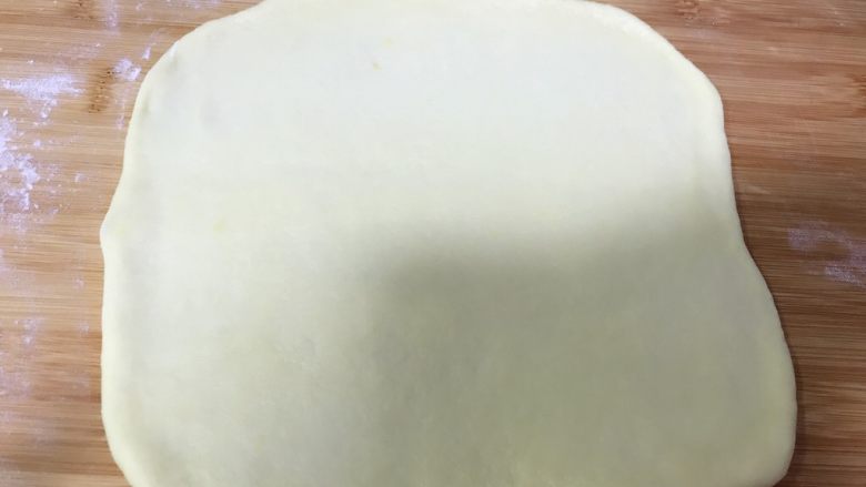 毛毛虫🐛牛角🥐辫子面包,把拿出来的一个小面团擀成饼皮，不用特别薄，差不多就可以了，然后铺上一层红豆沙。