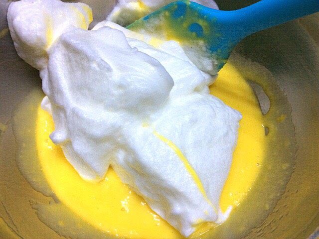 彩色戚风小蛋糕,取一半蛋白放入蛋黄糊中搅拌均匀，从底部往上翻拌，不要搅动