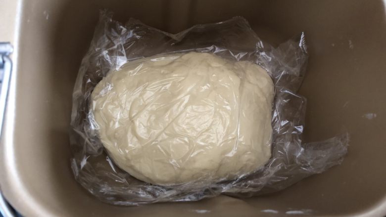 蜜豆小餐包,整理铺平在面包机内，盖上保鲜膜松弛5分钟，再开启发酵模式