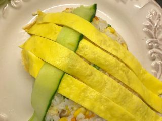 菠萝造型炒饭,黄瓜提前削片，将黄瓜片和鸡蛋皮相互编织