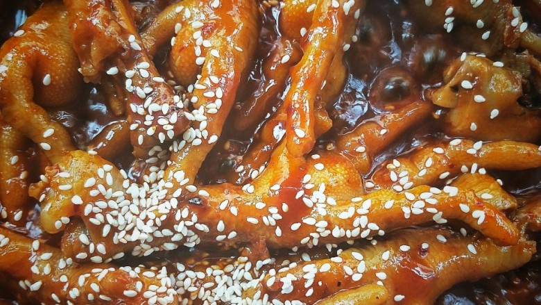入口即化的韩式辣鸡爪,关火，撒炒香的白芝麻，充分拌匀。