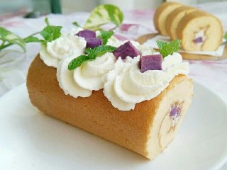 紫薯蛋糕卷,取出定型好的蛋糕卷，把奶油挤到上面。放几颗紫薯粒和薄荷叶。