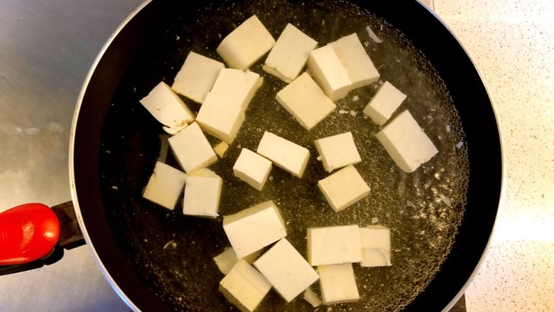 蟹黄豆腐,锅中下水煮开，放少量盐，加入豆腐焯水5分钟。这样既可以去豆腥味又能保持豆腐形状不易破碎。
焯水后取出沥干水分。
