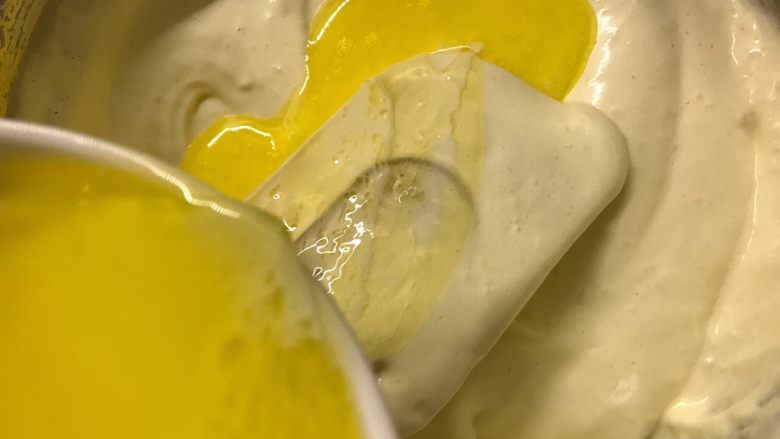 奶油纸杯蛋糕,将混合的黄油和牛奶分两次慢慢倒在刮刀上流入面糊中