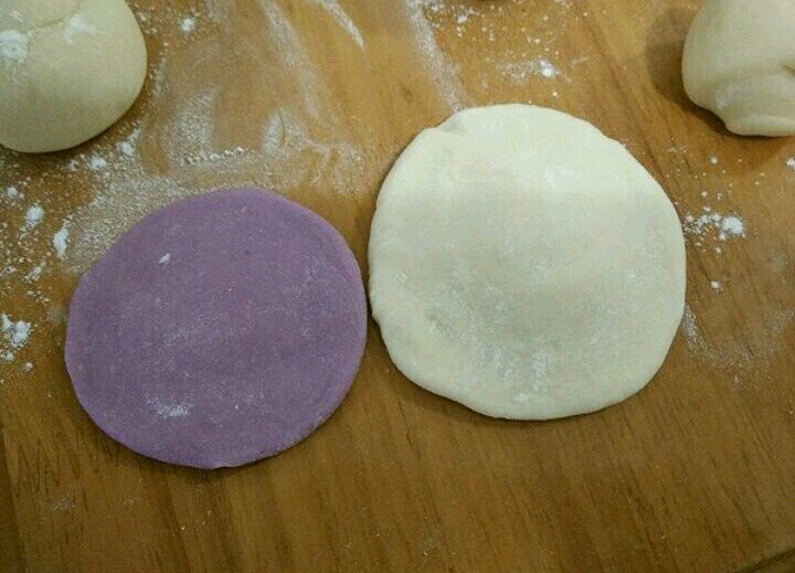 紫薯刺猬包子,取一个白色和紫色剂子，分别擀成中间厚的圆形。