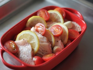 迷迭香柠檬烤翅,将蒜、小番茄、柠檬片放置在鸡翅的缝隙处。