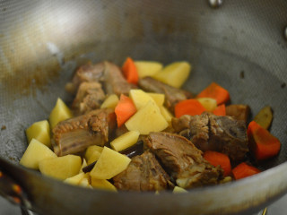 土豆排骨焖饭,接着放入土豆、胡萝卜拌炒均匀后关火