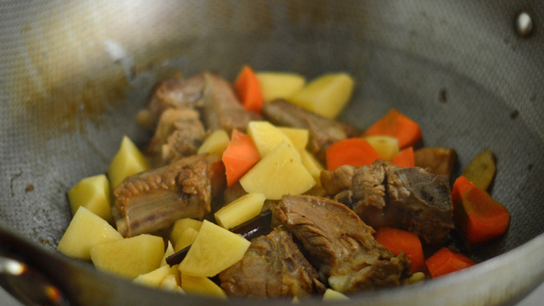 土豆排骨焖饭,接着放入土豆、胡萝卜拌炒均匀后关火