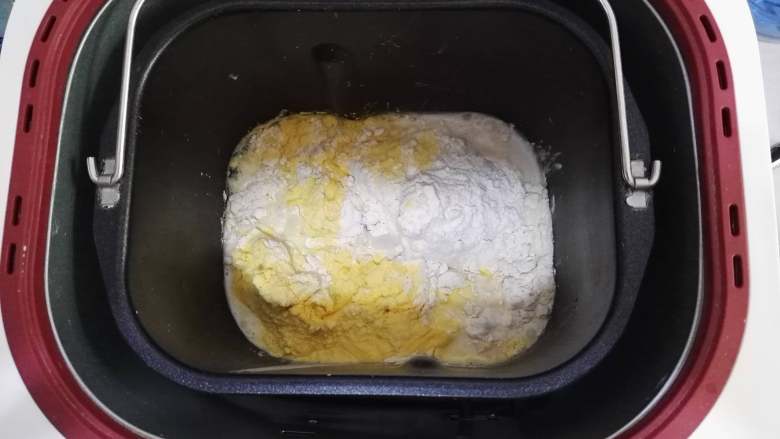 卷卷椰蓉包,面包机桶里，加入牛奶与酵母的混合液，加入面包粉、白糖、玉米粉，启动和面程序。