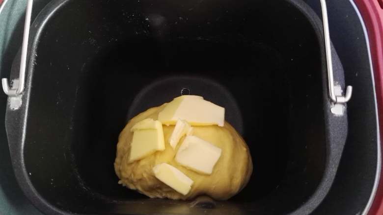 卷卷椰蓉包,面团揉出薄膜时，加入软化的黄油，继续揉面。