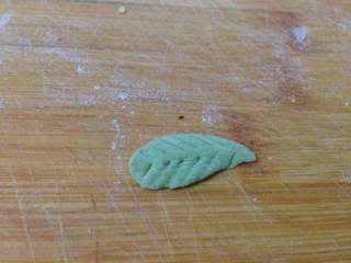 太阳花枣馍,取少许绿色面团搓成水滴形，
压扁，用牙签压出叶脉