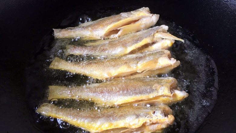 避风塘炒小黄鱼,将鱼的两面煎至浅金黄色，第一次定型完成，盛出备用。