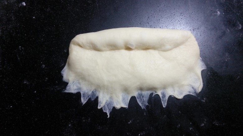 炼奶辫子面包,翻面后，压薄底边，自上而下卷起，中间尽量不要有空气.