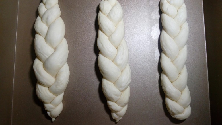 炼奶辫子面包,依次编好三根辫子。放入烤盘，整理好形状和位置，开始二次发酵。