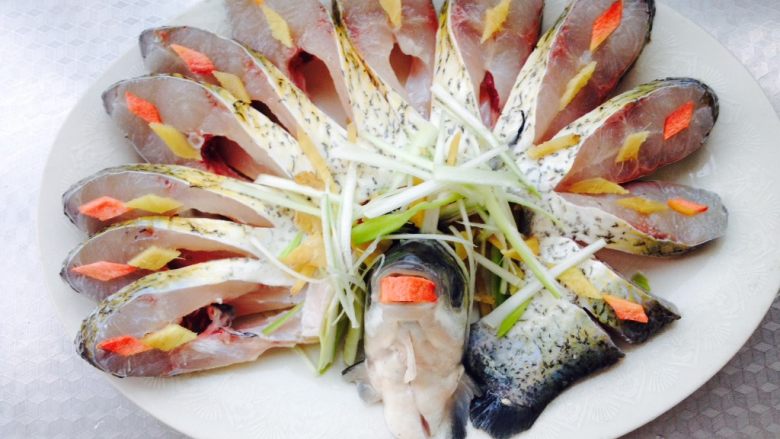 孔雀开屏鱼,将鱼摆入盘中，鱼头放中间，鱼身环绕，放上葱姜丝，胡萝卜片和姜片