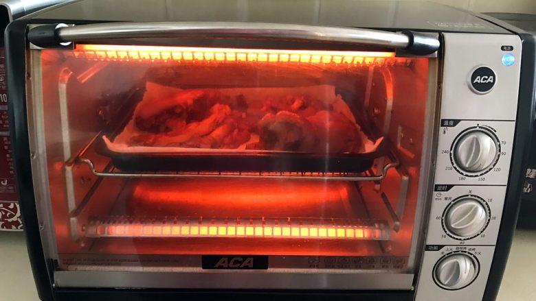 香辣烤猪手,把烤盘放入预热好的烤箱里，上下火200W烤5分钟