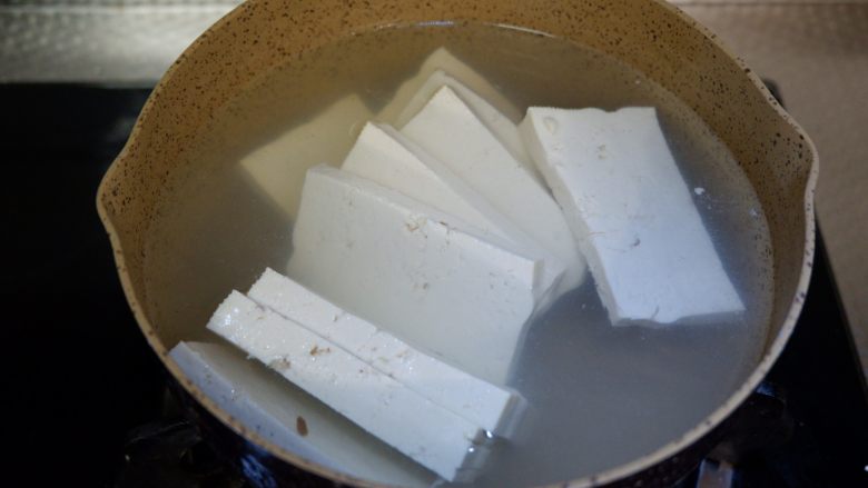 红白豆腐炖肉末,锅中烧开水，先将豆腐放入沸水中焯一下，捞出沥干水。