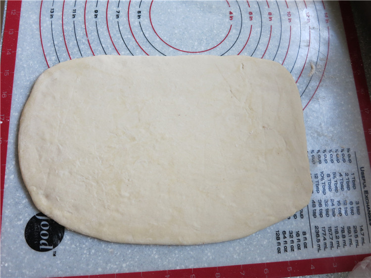 新网宠面包“白富美”净净包,冰箱取出冷藏的面团在胶垫上撒一些面粉防粘，擀开成长方形，大小正好可以包入擀薄的黄油片