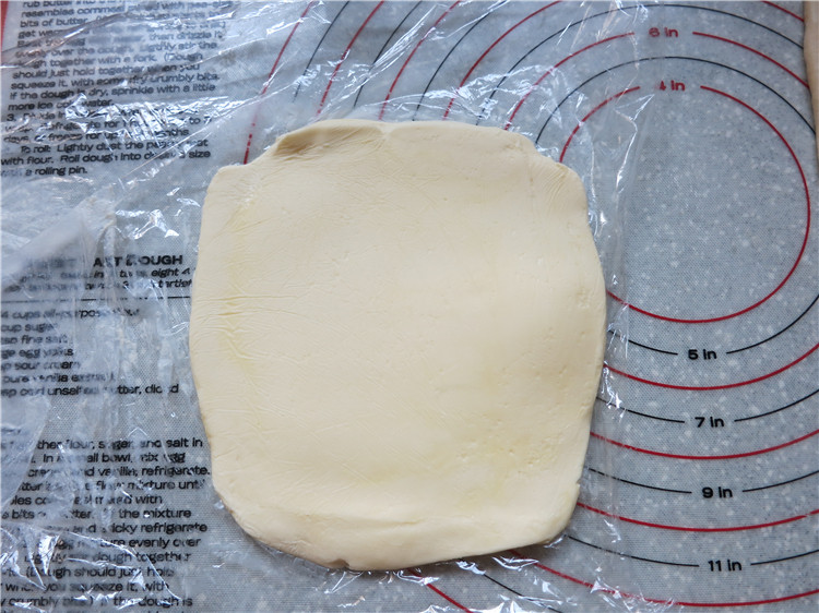 新网宠面包“白富美”净净包,将145克片状黄油包在保鲜膜里，先用擀面杖上下左右敲打几下，然后擀成正方形，大小正好可以包入面团中即可，擀好的黄油要与面团软硬度一致
