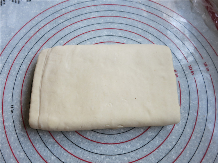 新网宠面包“白富美”净净包,将冷藏好的面团取出放在撒了少许面粉的胶垫上，再次擀开擀成长长的大面片在上下各1/3处折叠，完成3次3折，入冰箱冷藏松弛30分钟。