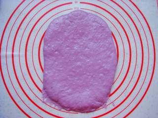 紫薯葡萄干欧包,取一个面团擀成长条薄面片，末端压薄（利于封口）