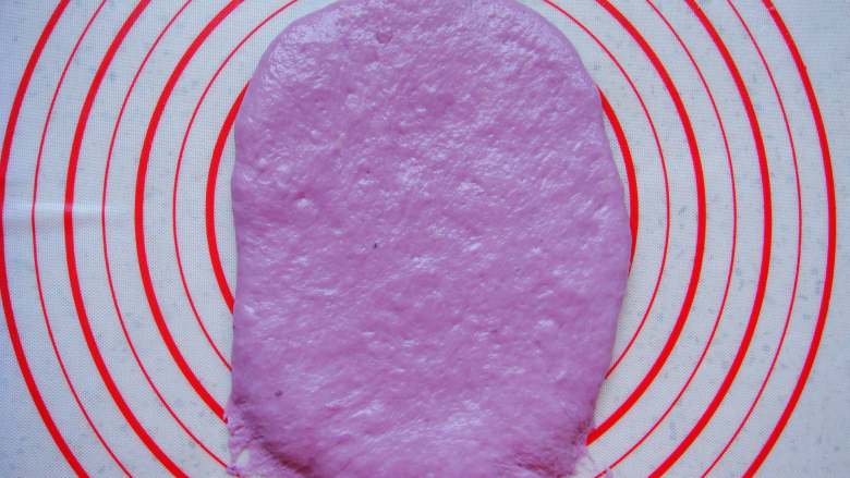 紫薯葡萄干欧包,取一个面团擀成长条薄面片，末端压薄（利于封口）