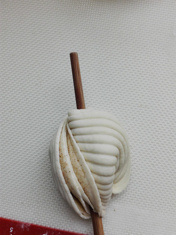 贝壳椒盐花卷,双手拧面团，反向旋转360度，把筷子在案板上轻轻按下，一个花卷完成