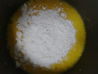 电饭煲蛋糕,将称好的低筋面粉筛入蛋黄液中，过筛的面粉做出的蛋糕口感才会好，不会有颗粒，如果没有低筋面粉，可以用玉米淀粉，普通面粉来做4:1的比例。面粉4玉米淀粉1