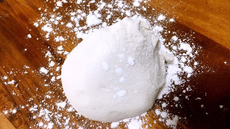 手工制作汤圆,面板上撒上些糯米粉，取一块面团。