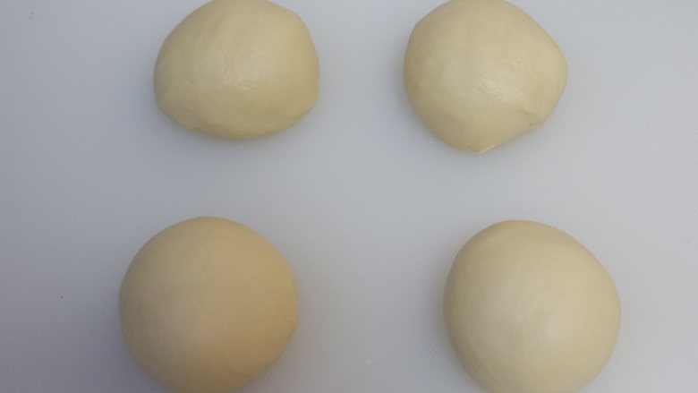 豆沙蛋黄面包,将面团平均分成4份，滚圆盖上保鲜膜松弛15分钟。 松弛时间取出椰蓉馅，也平均分成8份搓成圆球。
