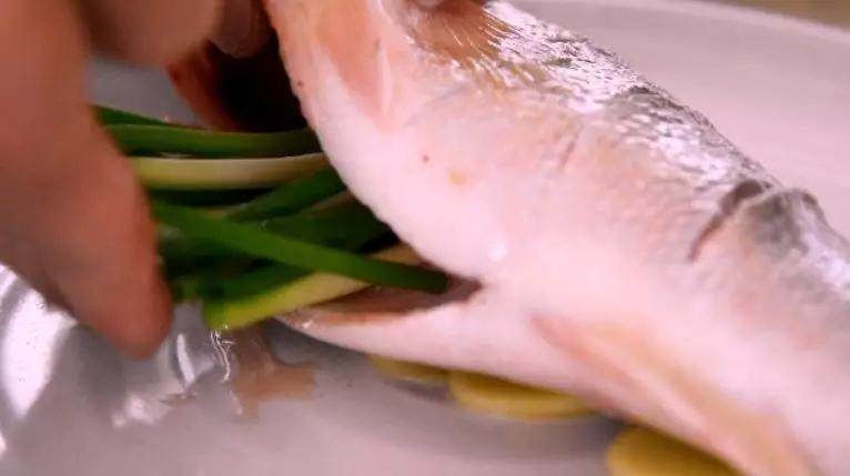 清蒸鲈鱼——蒸鱼好吃又不腥的小秘密都在这里了,腌制10分钟后，将鱼置于姜片上，腹中塞入葱段