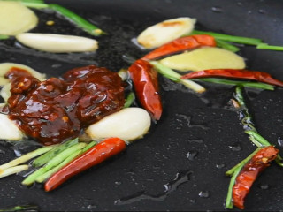 唤醒味蕾的极致美味—红红火火香辣虾,热锅冷油，放入姜片、蒜头、干辣椒、葱段、豆瓣酱炒出红油。
再把炸虾放入锅中炒。