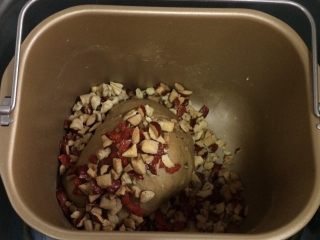 红枣枸杞软欧包,把红枣、核桃碎和枸杞子一起倒入面包机桶内和2～3分钟，也可以直接用手把馅料包入面团中。