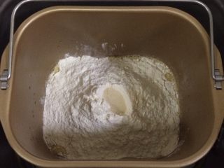 红枣枸杞软欧包,除黄油以外的面包材料都放入面包机内（先液体后粉类的顺序），在面粉中间挖个洞，把酵母粉倒入，启动和面程序。