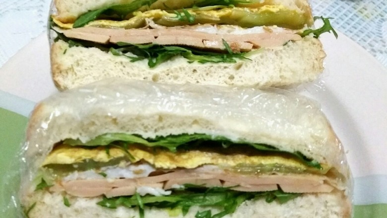 花样吃吐司――早餐三明治,切开，用保鲜膜在切的时候可以起到固定的作用，吃起来也更方便。三明治就做好啦，可以享用啦。