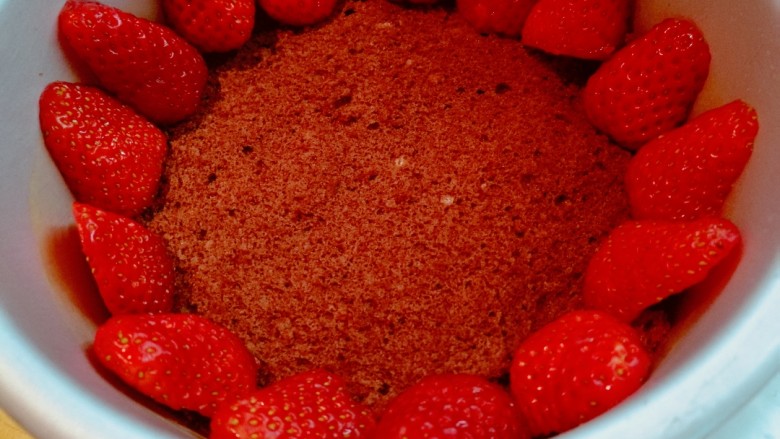 草莓奶酪慕斯蛋糕,牛奶草莓用淡盐水洗净，切去底部，将一半草莓对半切开，在第一层蛋糕上摆上草莓。