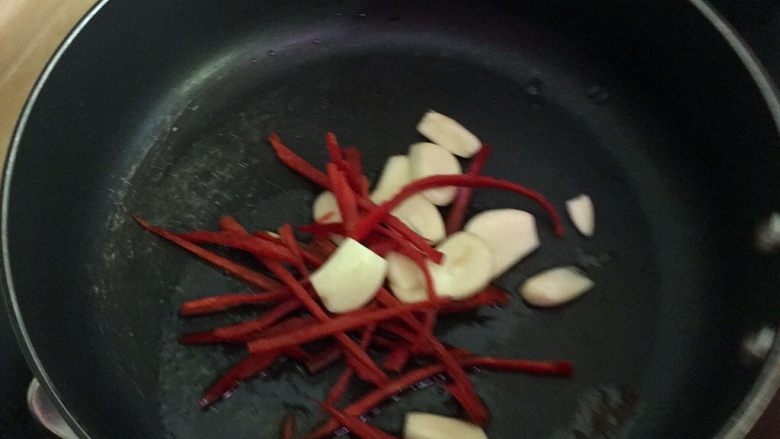 干煸鱿鱼,热锅下色拉油爆香红椒段及蒜片