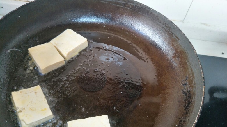 椒盐煎豆腐,待油温六七成热，把豆腐放入平底锅中。