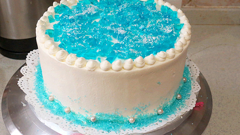 【冰雪奇缘主题生日蛋糕】,蛋糕顶部边缘挤上小圆球，中间放上蓝色果冻，底部撒上蓝色装饰糖粒