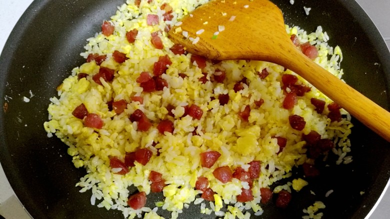 腊肠黄金炒饭,用锅铲继续翻炒，把米饭和腊肠炒匀。