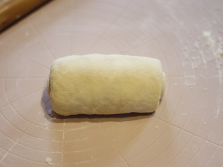 原味基础吐司（面包机版）,将面饼从一端向另一端卷起，形成一个面卷。
