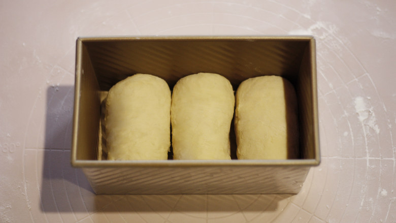 原味基础吐司（面包机版）,三个面团全部卷好后，一次排入土司模子中。
放好的面团放入烤箱，38度再次发酵40分钟。